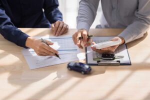 A couple reviews a printed insurance statement with a pen and calculator at a kitchen table.